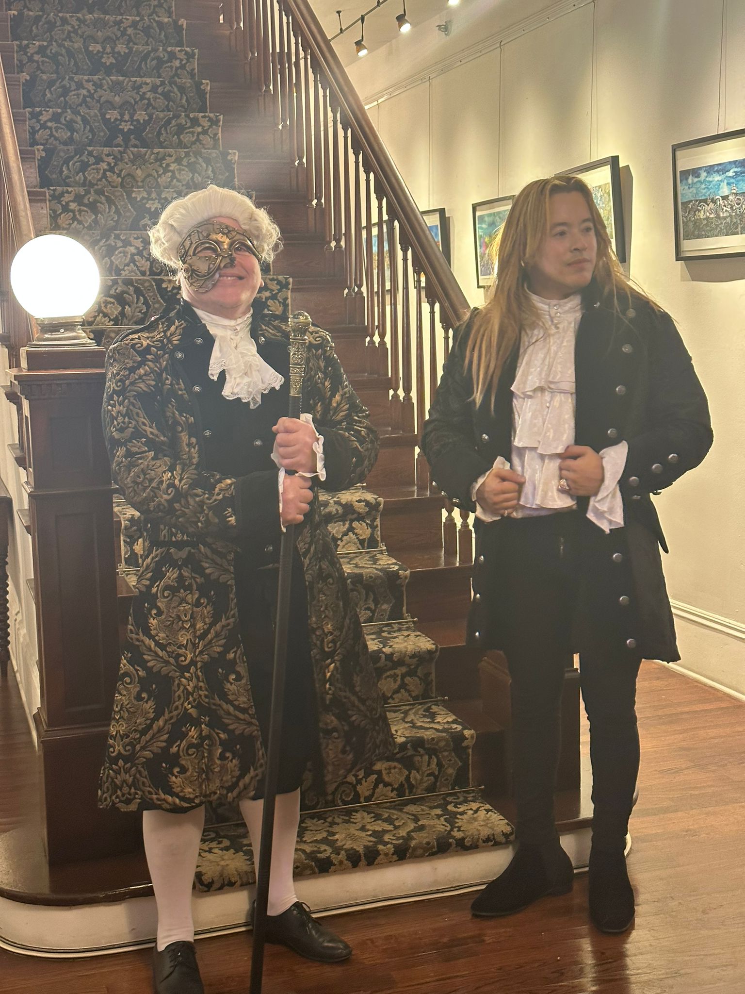 Two men in Victorian coats by a staircase